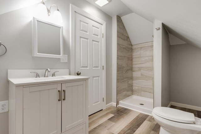 bathroom with a tile shower, wood-type flooring, vaulted ceiling, and toilet