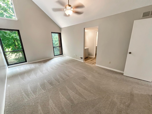 spare room featuring light carpet, high vaulted ceiling, ceiling fan, and a healthy amount of sunlight