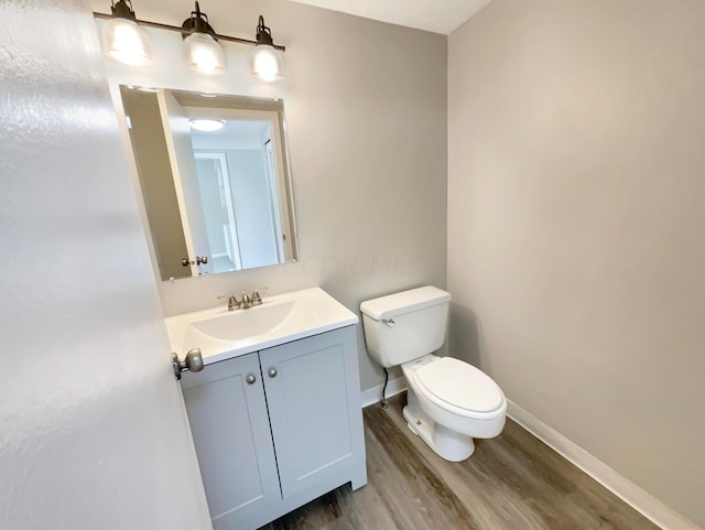 bathroom with hardwood / wood-style flooring, vanity, and toilet