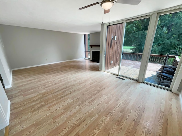 unfurnished living room featuring ceiling fan, plenty of natural light, and light hardwood / wood-style floors