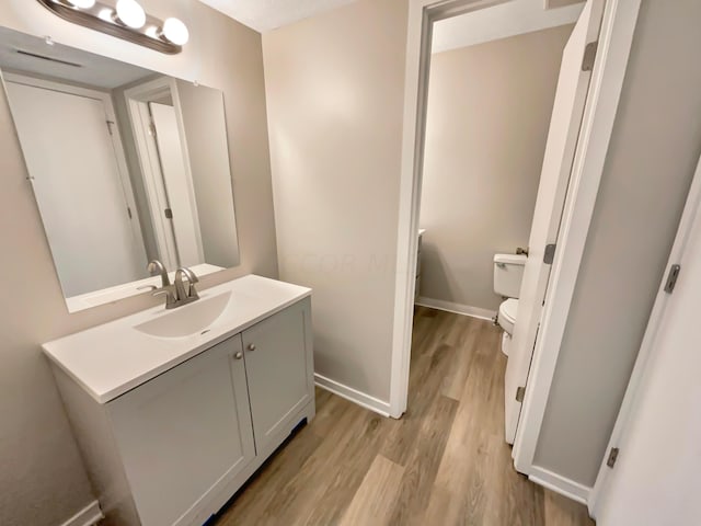 bathroom with vanity, wood-type flooring, and toilet