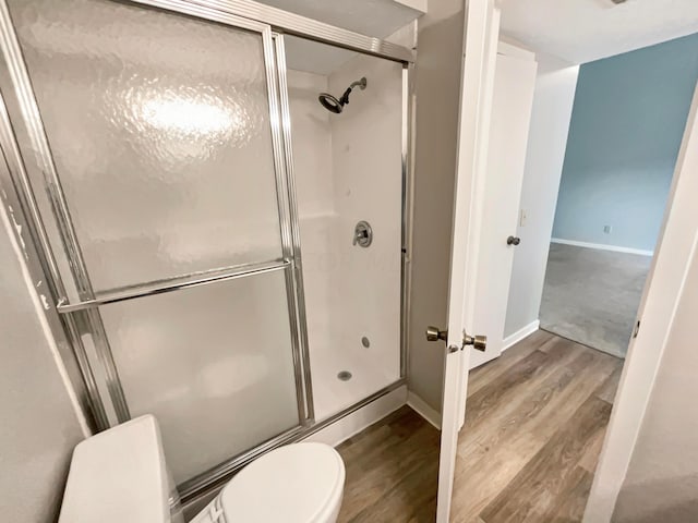 bathroom featuring toilet, an enclosed shower, and hardwood / wood-style flooring