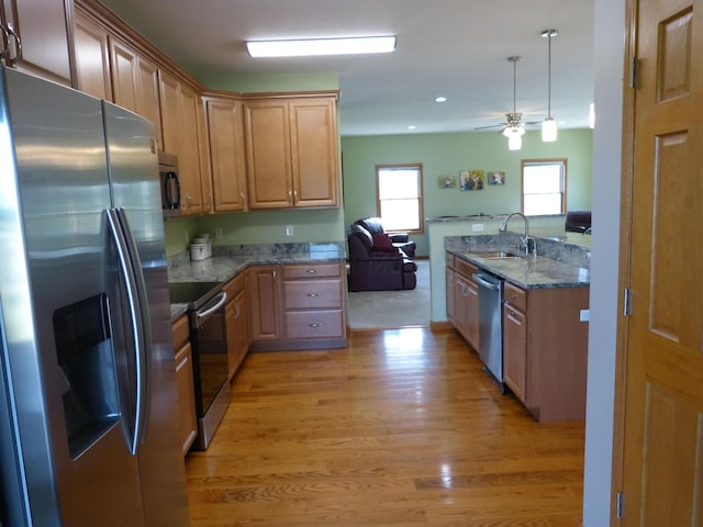 kitchen featuring sink, ceiling fan, light hardwood / wood-style floors, light stone counters, and stainless steel appliances