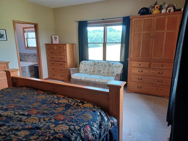 bedroom with ensuite bathroom and light carpet