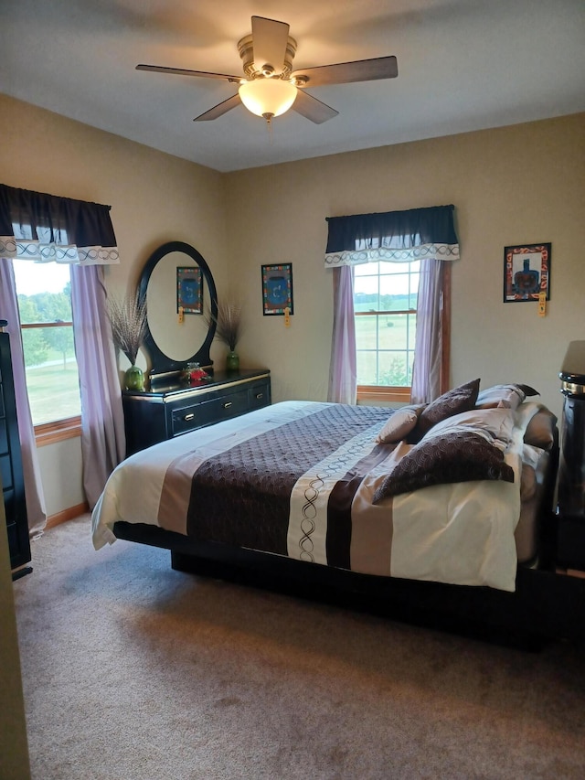 bedroom with multiple windows, ceiling fan, and carpet