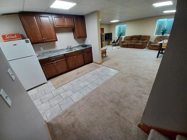 kitchen featuring white fridge, a drop ceiling, light colored carpet, and sink