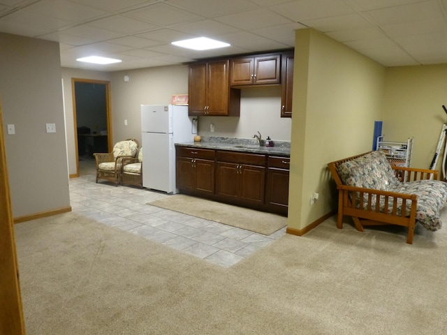 kitchen featuring dark brown cabinetry, light carpet, sink, and white refrigerator