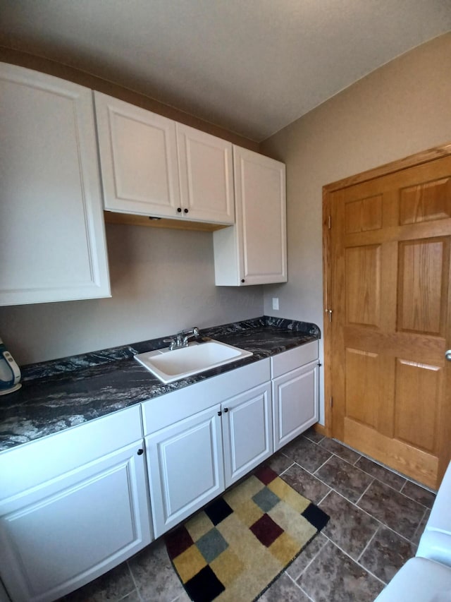 kitchen featuring white cabinetry, sink, and dark tile patterned floors