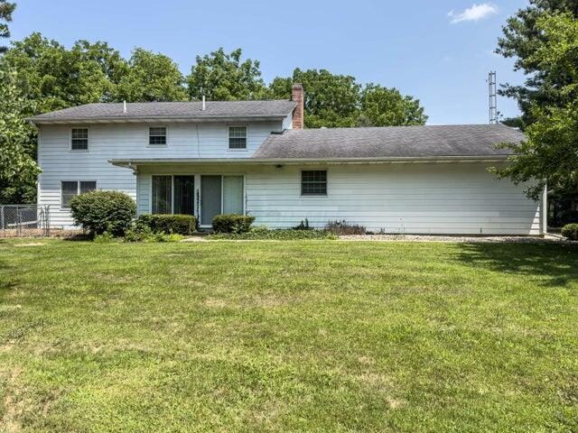 rear view of house featuring a lawn