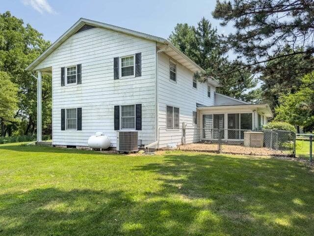 back of house featuring a sunroom, a yard, and cooling unit