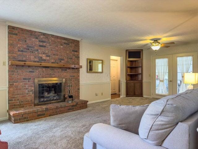 living room featuring carpet flooring, french doors, a textured ceiling, and a fireplace