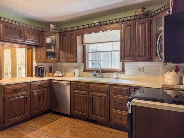 kitchen with backsplash, stainless steel appliances, light hardwood / wood-style floors, and sink