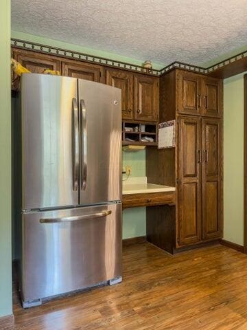 kitchen with stainless steel fridge, a textured ceiling, and hardwood / wood-style flooring