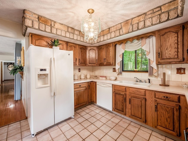 kitchen with decorative backsplash, white appliances, a textured ceiling, sink, and pendant lighting