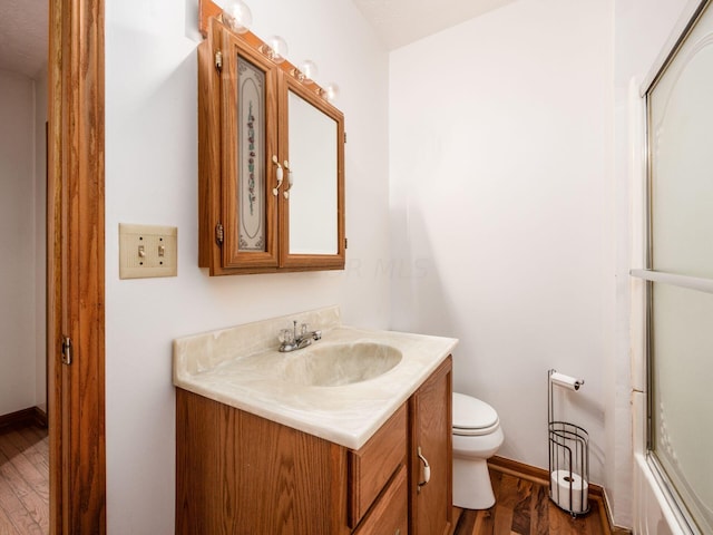 bathroom with toilet, vanity, and hardwood / wood-style flooring