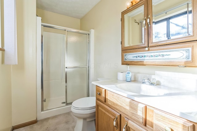 bathroom featuring a textured ceiling, vanity, toilet, and a shower with shower door