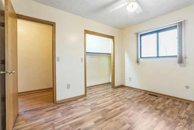 unfurnished bedroom with a textured ceiling, a closet, light hardwood / wood-style floors, and ceiling fan