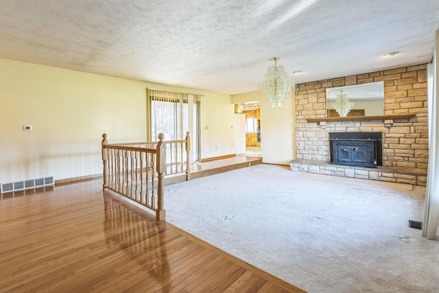 unfurnished living room with a chandelier, a textured ceiling, and hardwood / wood-style flooring