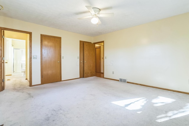 unfurnished bedroom featuring ceiling fan, light carpet, and connected bathroom