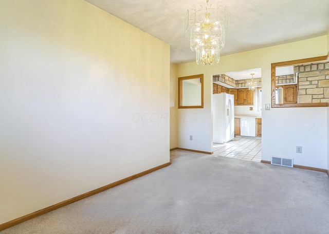 spare room featuring light carpet and a notable chandelier