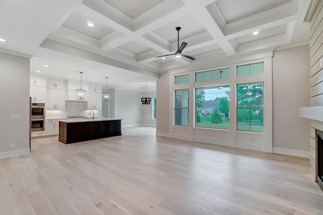 unfurnished living room featuring ceiling fan, sink, coffered ceiling, light hardwood / wood-style flooring, and beamed ceiling