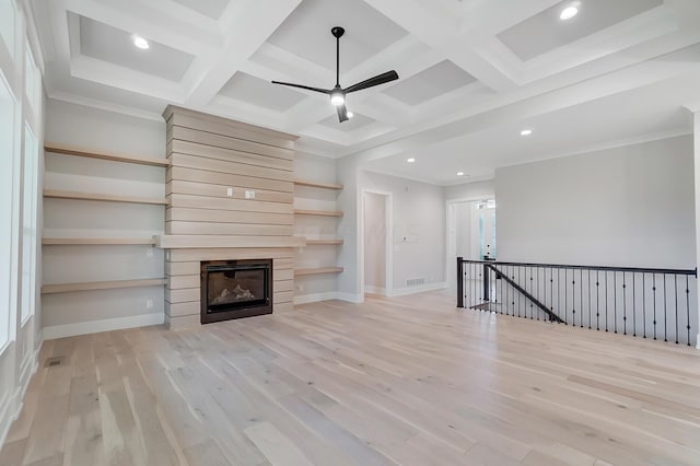 unfurnished living room featuring coffered ceiling, ceiling fan, light wood-type flooring, beam ceiling, and a large fireplace