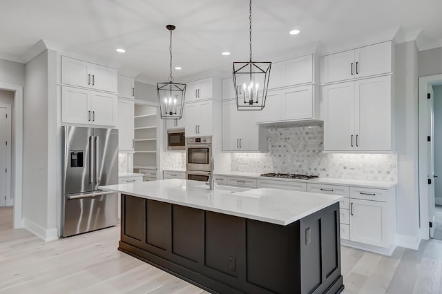 kitchen featuring white cabinets, appliances with stainless steel finishes, decorative light fixtures, and a kitchen island with sink