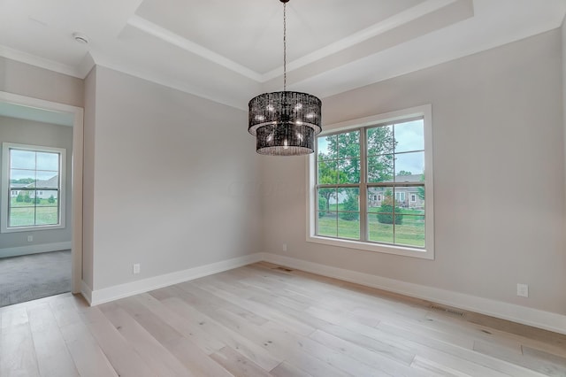 spare room featuring a tray ceiling, a chandelier, and light wood-type flooring