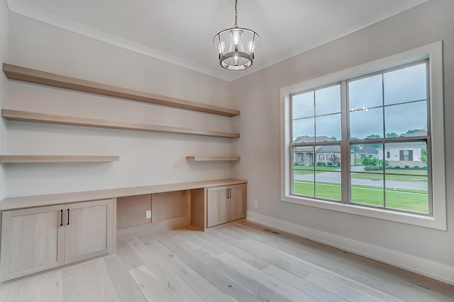 unfurnished office with light wood-type flooring, built in desk, an inviting chandelier, and crown molding