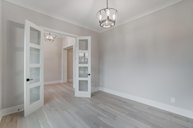 spare room with french doors, light hardwood / wood-style flooring, an inviting chandelier, and crown molding