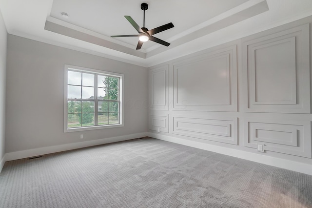 carpeted empty room featuring a raised ceiling and ceiling fan