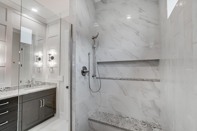 bathroom with tiled shower and vanity