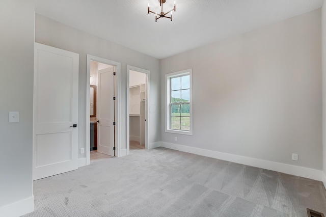 interior space featuring a notable chandelier, a walk in closet, light carpet, and a closet