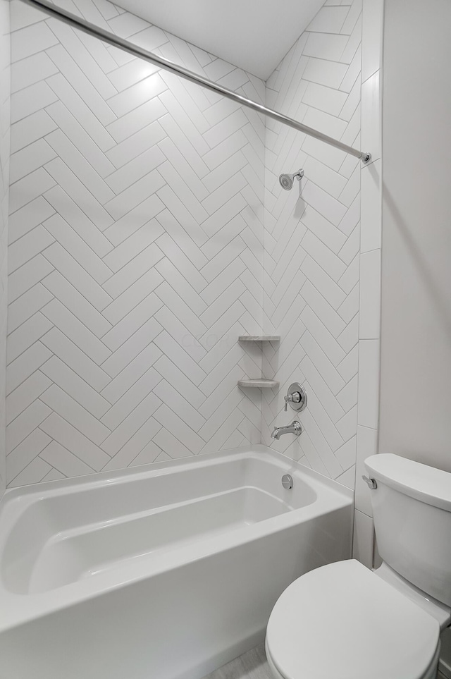 bathroom with tiled shower / bath combo and toilet