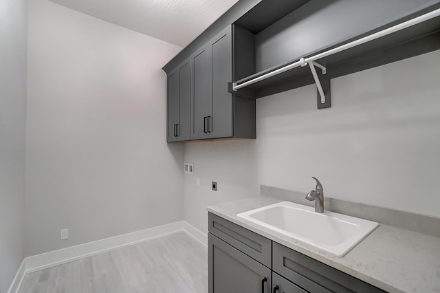 clothes washing area featuring hookup for an electric dryer, washer hookup, cabinets, sink, and light hardwood / wood-style floors