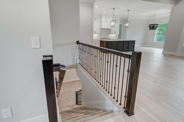 stairway featuring hardwood / wood-style floors, a chandelier, and sink