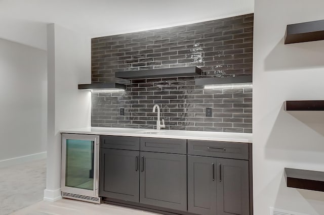 bar with tasteful backsplash, wine cooler, gray cabinetry, and sink