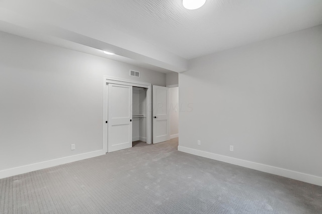 unfurnished bedroom featuring light carpet and a closet