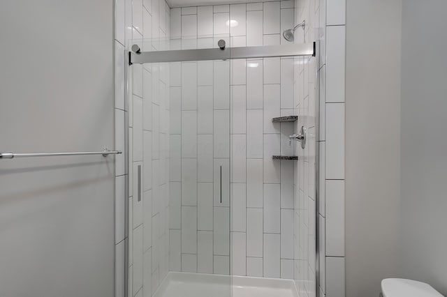 bathroom featuring toilet and a shower with shower door