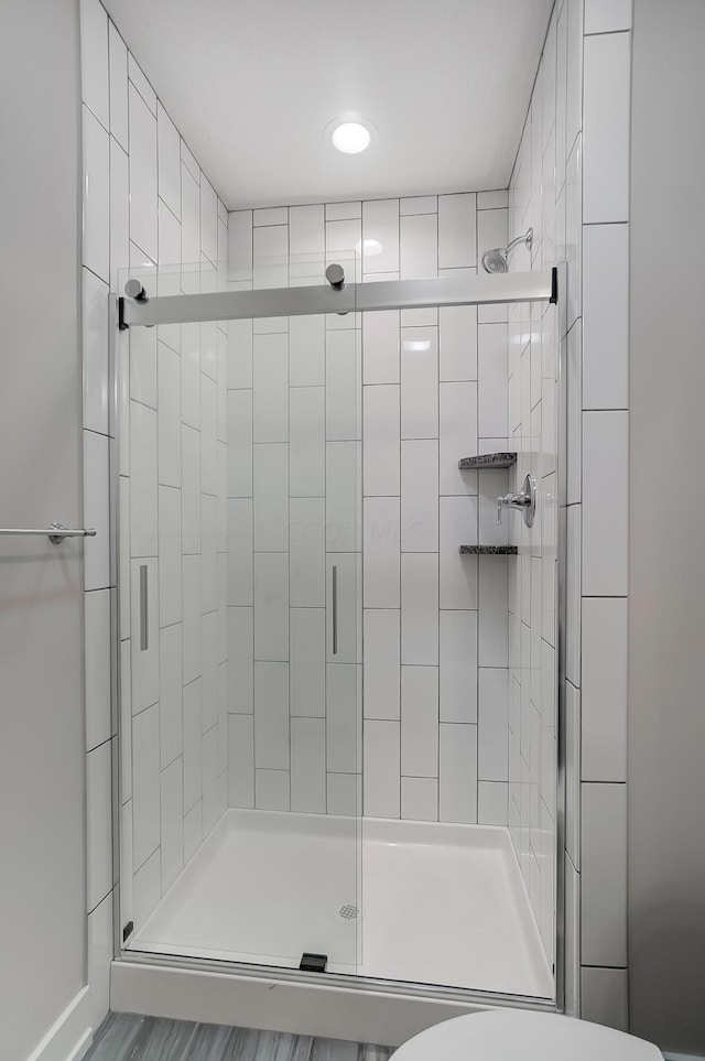 bathroom featuring hardwood / wood-style floors, toilet, and a shower with door