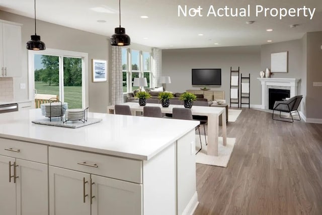 kitchen featuring pendant lighting, light wood-type flooring, white cabinetry, and backsplash