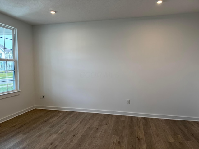 spare room featuring a textured ceiling and dark hardwood / wood-style floors