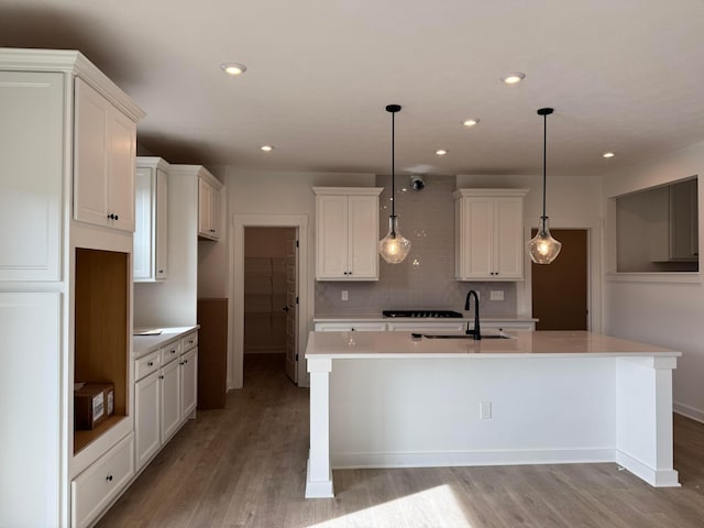 kitchen featuring white cabinets, sink, and a kitchen island with sink