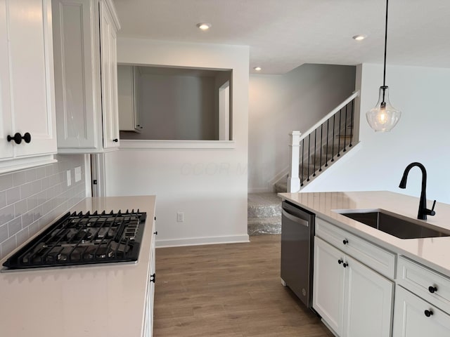 kitchen featuring sink, hanging light fixtures, black gas cooktop, stainless steel dishwasher, and hardwood / wood-style floors