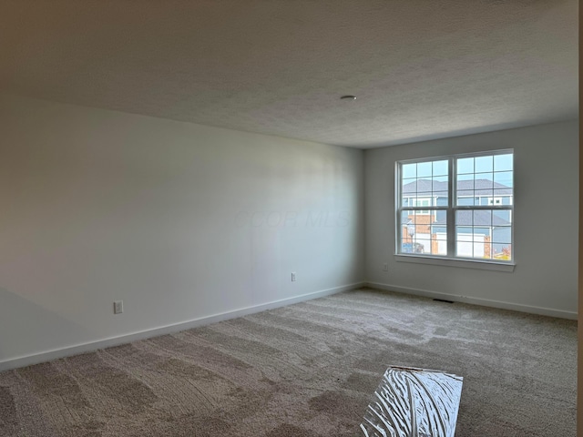 unfurnished room with a textured ceiling and carpet floors