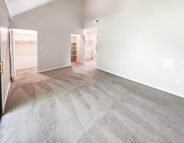 carpeted empty room with high vaulted ceiling