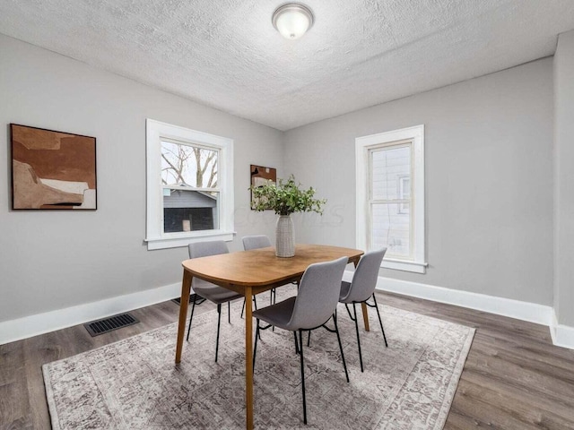 dining space with dark hardwood / wood-style flooring and a textured ceiling