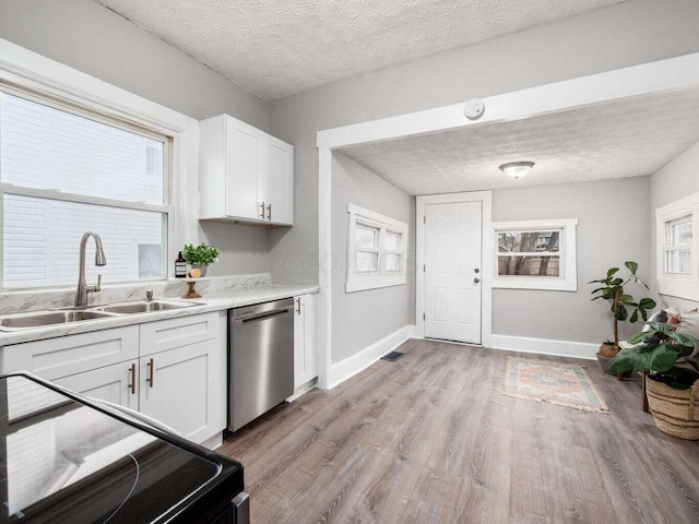 kitchen featuring white cabinets, sink, stainless steel dishwasher, a wealth of natural light, and light hardwood / wood-style floors