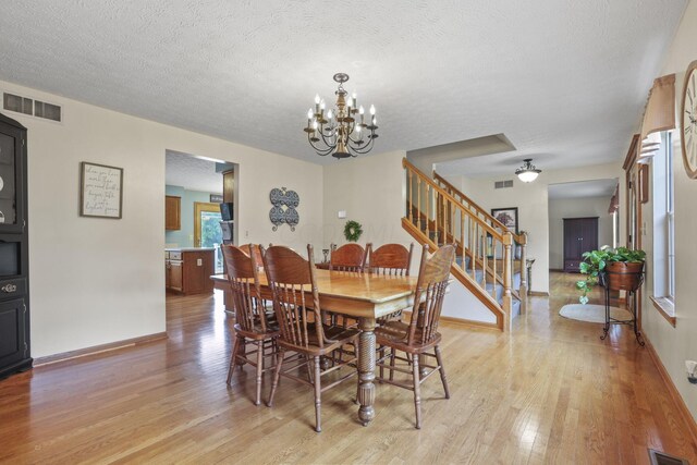 dining space with light wood-type flooring, a textured ceiling, and a chandelier