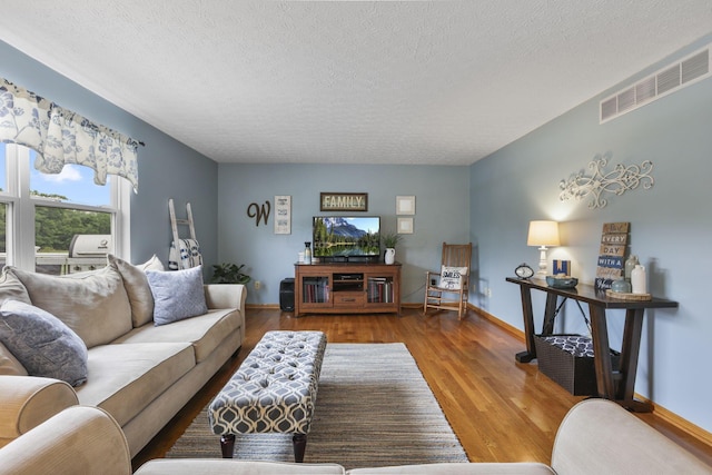 living room with wood-type flooring and a textured ceiling